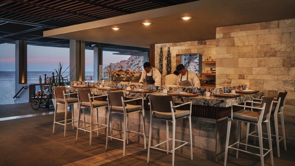 A bar with stools and a view of the ocean.