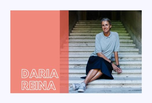 Daria Reina wearing a grey top and blue skirt sitting on stairs