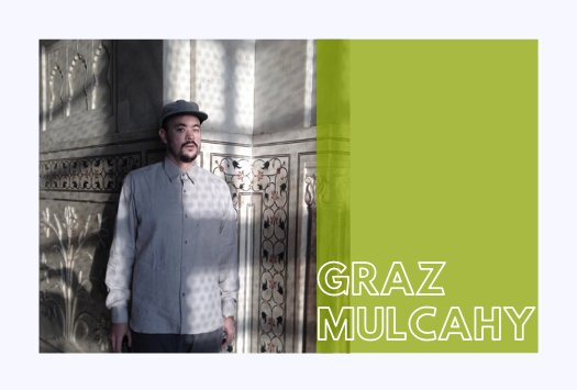 Graz Mulcahy standing in front of a wall made of embellished stone 