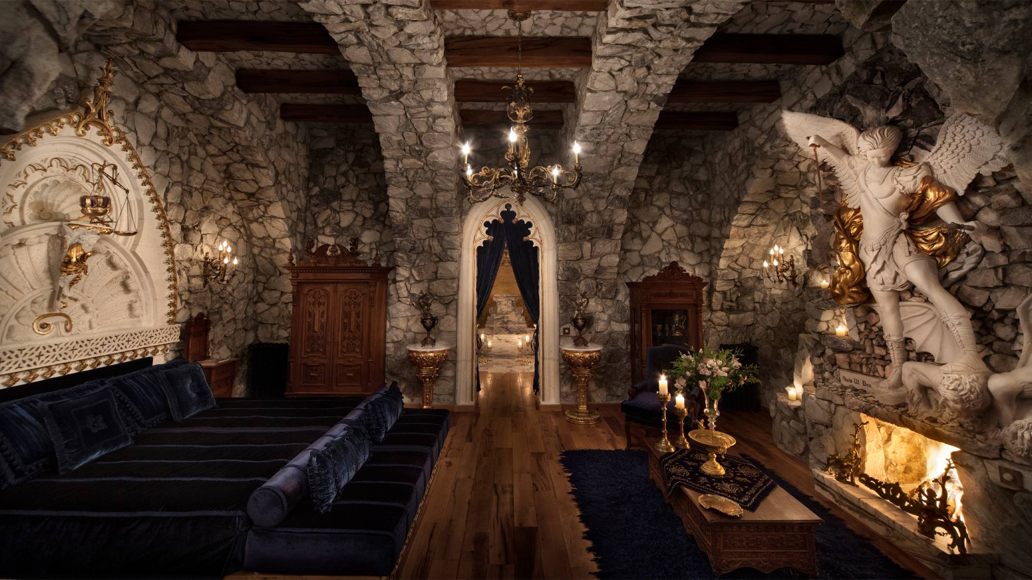 The inside of Sacred House, a boutique hotel with sculptures, stone walls and fireplace