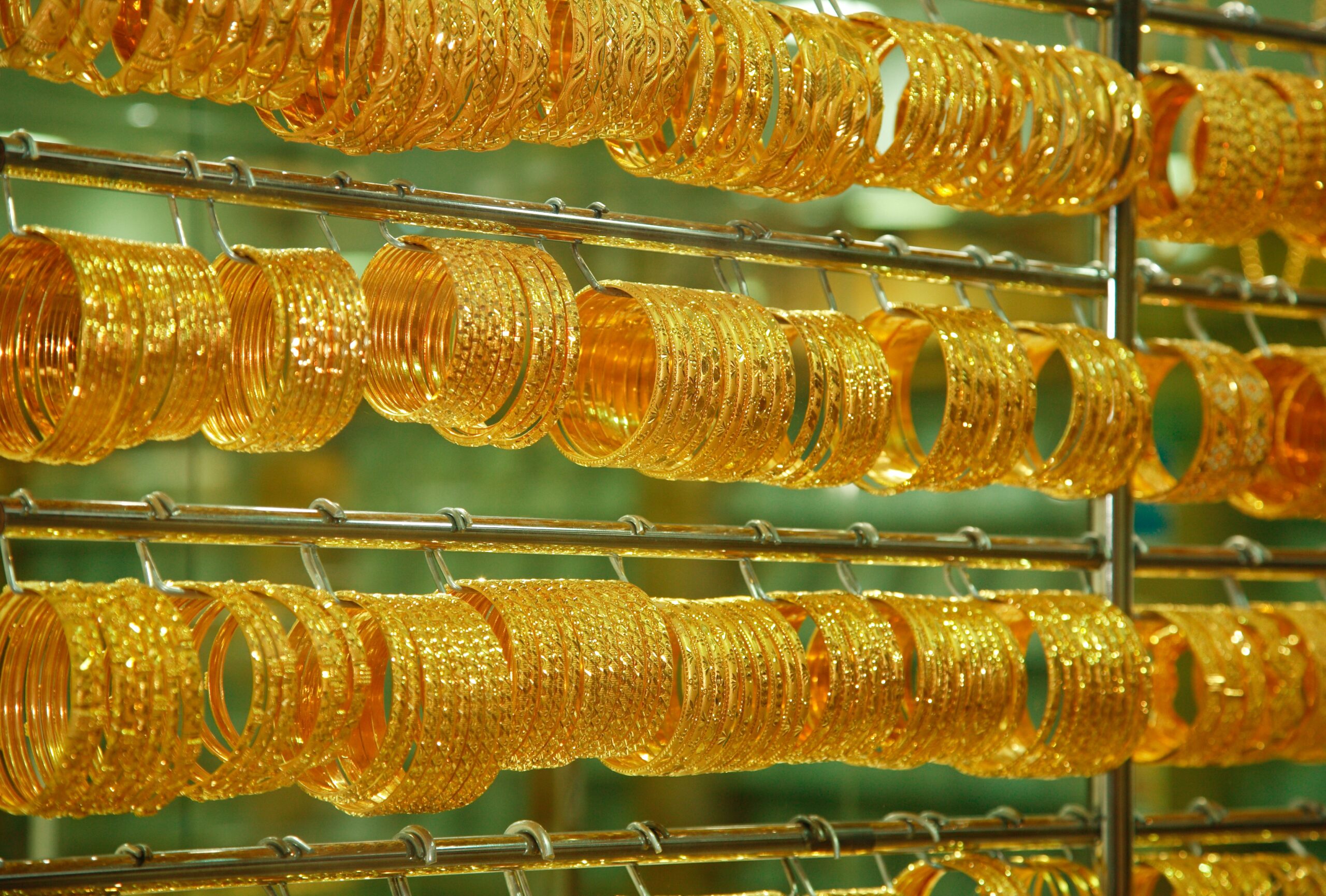 Shining gold bracelets hanging next to each other in 4 rows 