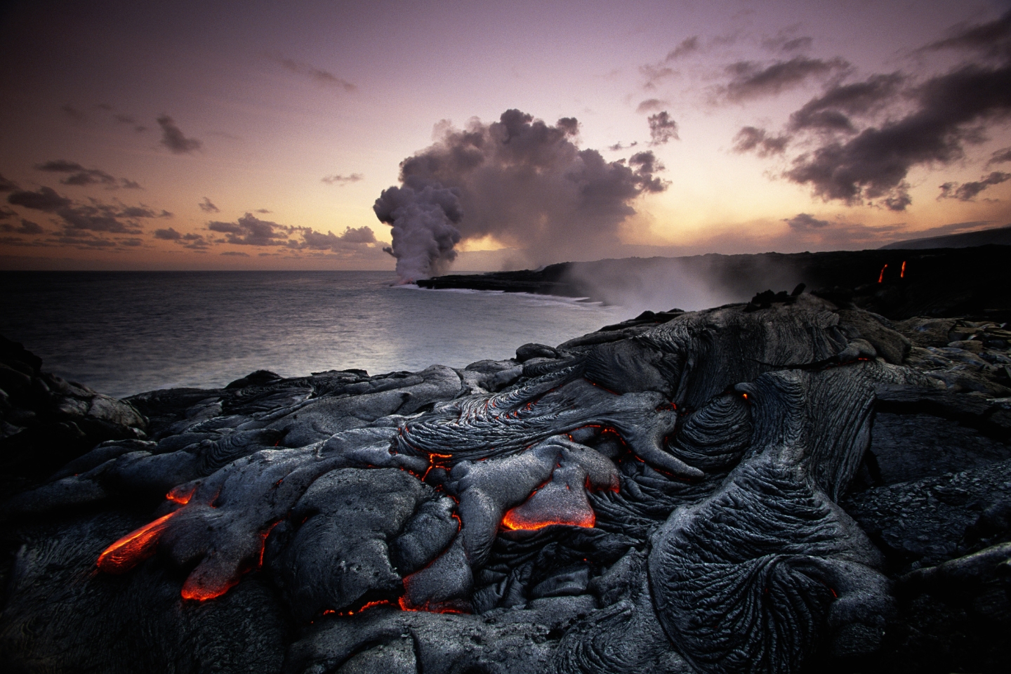 lava flows into the ocean at sunset in hawaii