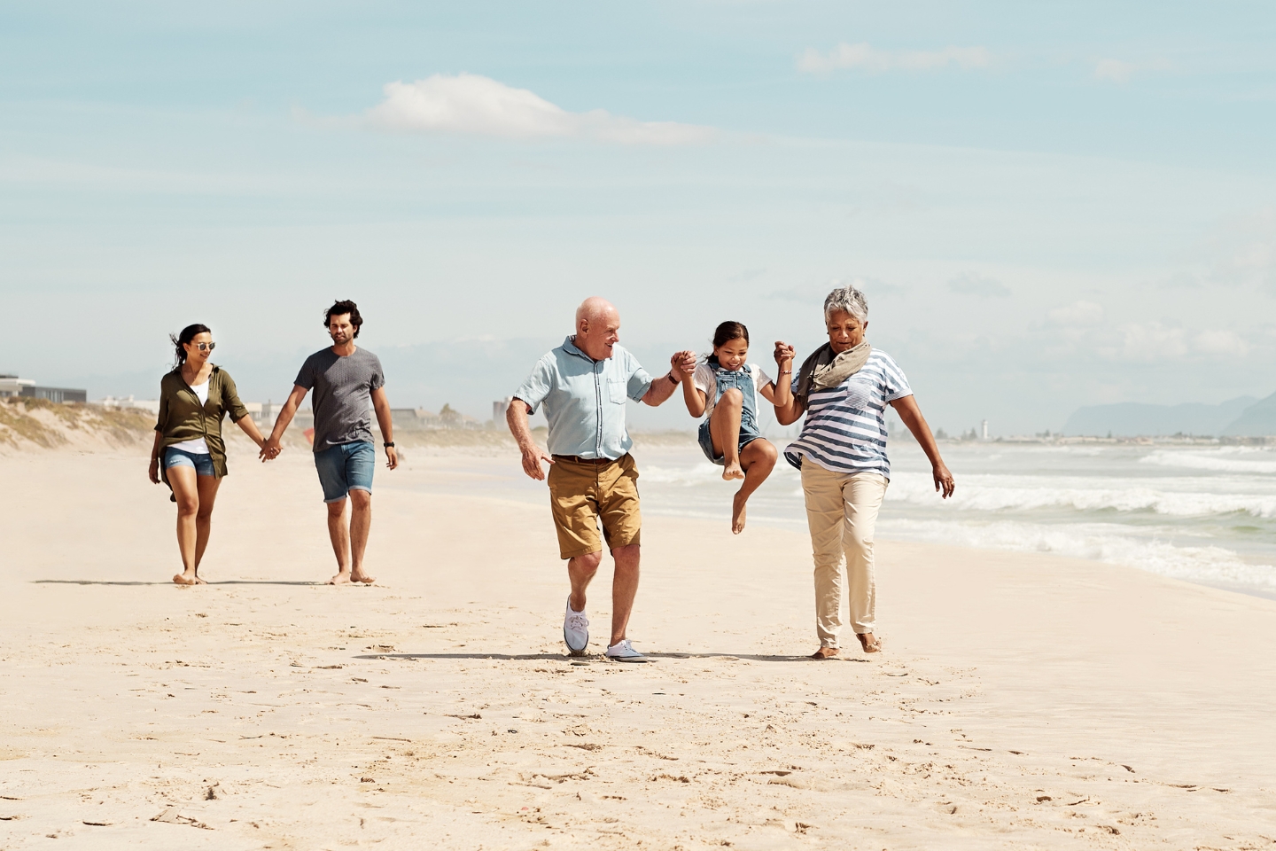 a group of people, a multi-generational family walking on the beach