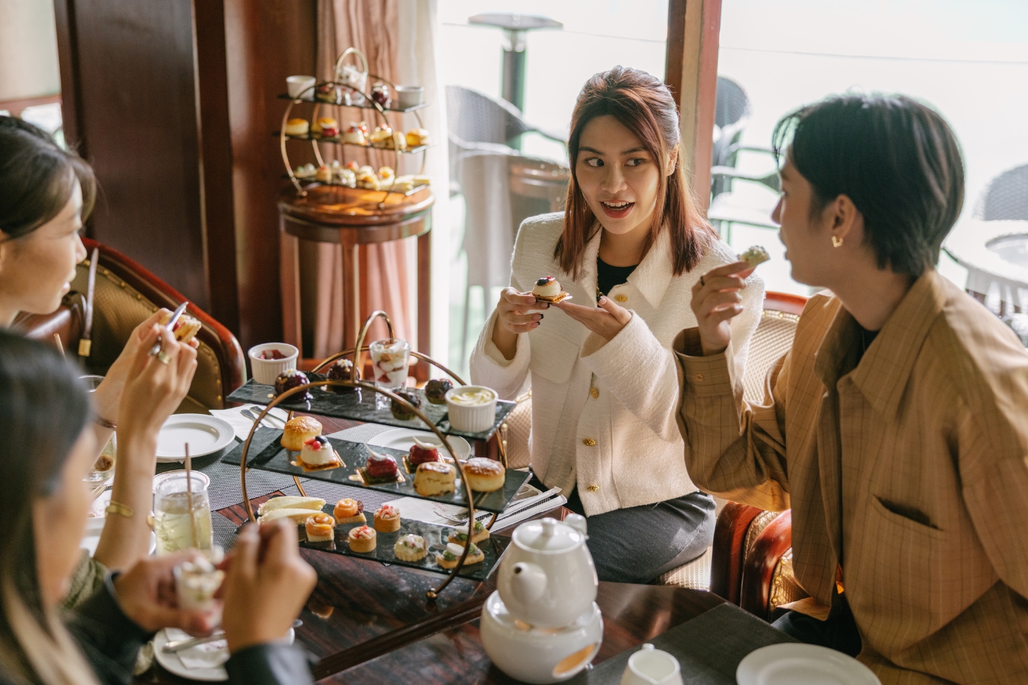 a group of people sitting at a table eating food, afternoon tea